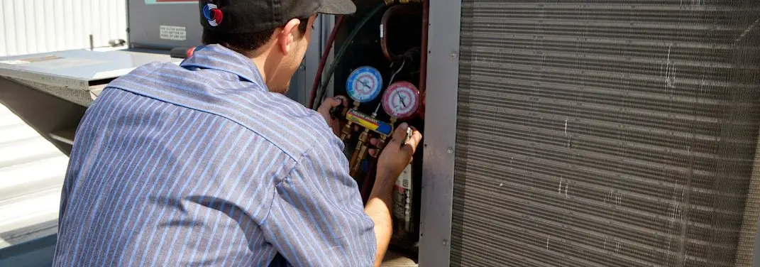 HVAC technician servicing a condenser unit in Gardiner